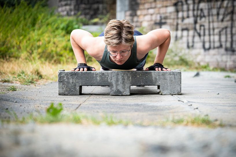 Active 36 year old white woman planking under a bridge outdoors, by Werner Lerooy