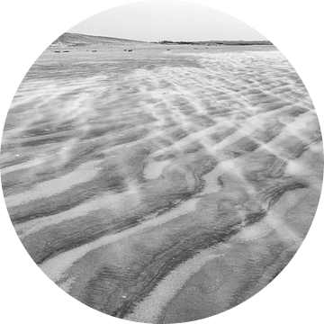 Wind dwarrelt over strand Ameland bij vuurtoren