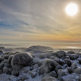 Een dicht gevroren IJsselmeer met ondergaande zon. van Bert de Boer