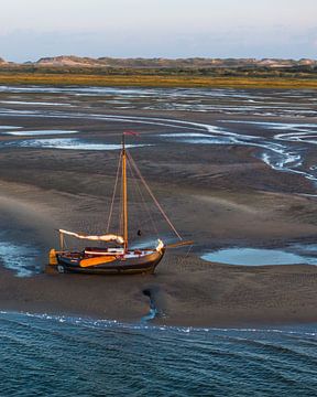 Sailboat running dry on the mud flats by Ewold Kooistra