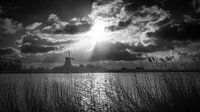 Zwart wit foto van een windmolen aan het water