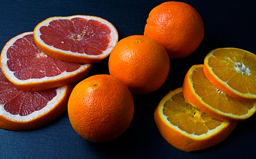 Grapefruit en sinaasappel in plakjes gesneden en gerangschikt op een zwarte serveerschaal