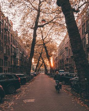 Fel oranje zonsondergang met een fietser op de Lomanstraat in Amsterdam van Michiel Dros