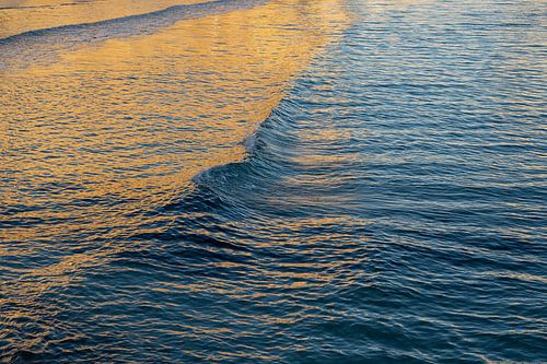 Gouden zeegolven bij zonsopgang