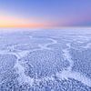 Schöne Strukturen auf einem eisbedeckten IJsselmeer im Winter. Am Horizont geht die Sonne langsam au von Bas Meelker