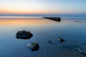 Pierres et poteaux sur la mer des Wadden à Wieringen au coucher du soleil