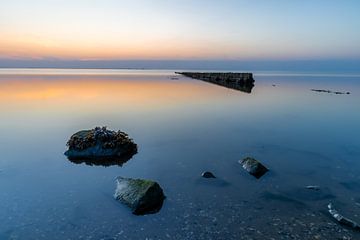 Stones and posts on the Wadden Sea on Wieringen during sunset by Bram Lubbers