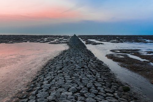 Drooggevallen pier in de Waddenzee bij zonsondergang.