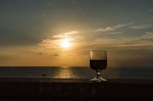 Nahaufnahme eines Weinglases vor einem romantischen Sonnenuntergang