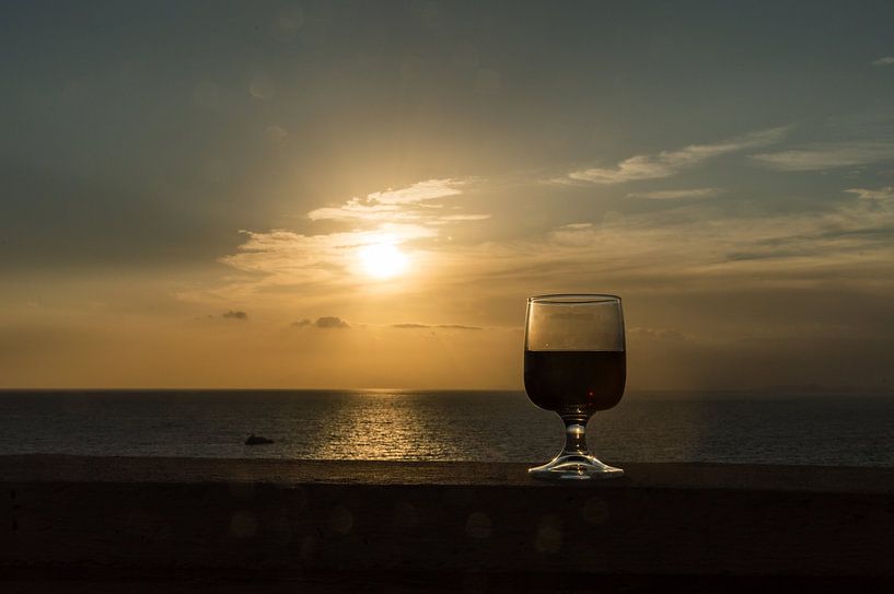 Nahaufnahme eines Weinglases vor einem romantischen Sonnenuntergang von Patrick Verhoef