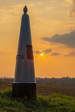 Grenspaal tussen Nederland en België in de weilanden bij Maastricht tijdens de zonsondergang van Kim Willems