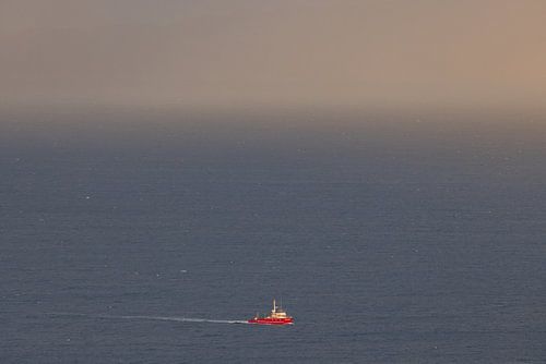 Rode vissersboot in de oceaan - rust en ruimte aan de horizon