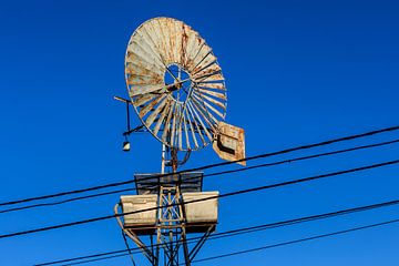 old rustic water pump windmill against clear blue sky by VIDEOMUNDUM