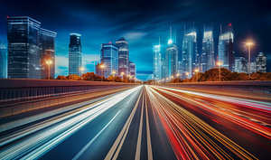Zeitraffer-Autolichtspuren auf der nächtlichen Stadtstraße mit Skyline im Hintergrund