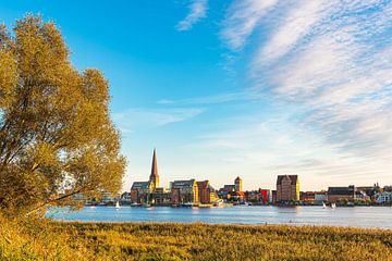 Uitzicht over de Warnow naar de Hanzestad Rostock bij avond van Rico Ködder