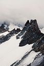 Bergspitze mit Schnee durch Wolken von Jacqueline Groot Miniaturansicht