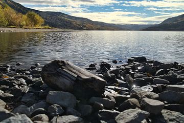 Rustig bergmeer met herfstheuvels en rotsen in het heldere water