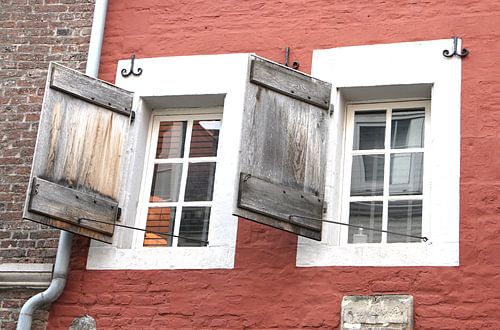 Old windows with wooden shutters on terracotta-coloured r