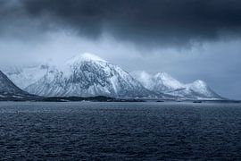 In Fiskebol, Lofo, ragen majestätische schneebedeckte Berge über tiefem Wasser empor von PhotoCluster