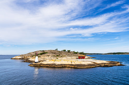 Un phare et une cabane en bois rouge sur une île de l'archipel près de Str