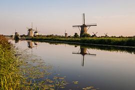 Childlike Windmills along the water. by Brian Morgan