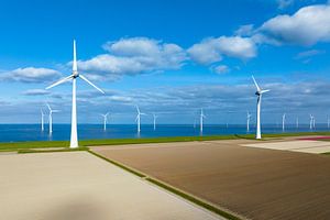 Windkraftanlagen auf einem Deich und vor der Küste im Frühling