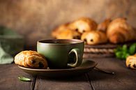 Green cup of tea with mini chocolate roll by Iryna Melnyk thumbnail