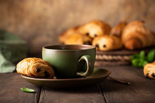 Green cup of tea with mini chocolate roll