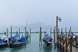 Venice gondolas resting in foggy winter lagoon by Tomherkules