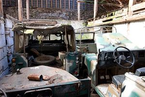 old vehicles are rusting in a farmer's barn