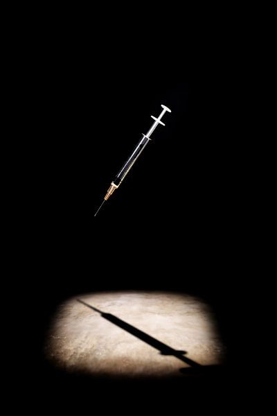 Spritze im dramatischen Spotlight auf Schwarz von Frank Heinz