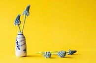 Antiek chinees vaasje met blauwe druifjes tegen een gele achtergrond van Marjolein Hameleers thumbnail