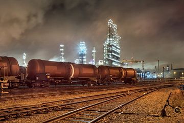 Oil refinery with train wagons at night by Tony Vingerhoets