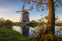 Windmill along the water during sunset