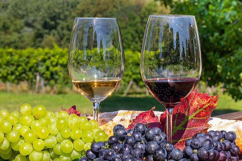 Ripe grapes decorated with wine glasses on a wooden table by Udo Herrmann
