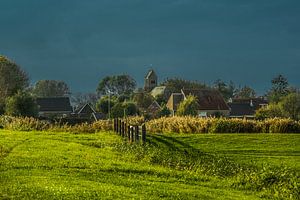 Het Friese dorpje Lichtaard in de nazomerzon met een donkere lucht op de achtergrond