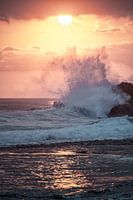 Les vagues du coucher de soleil s'écrasent contre les rochers