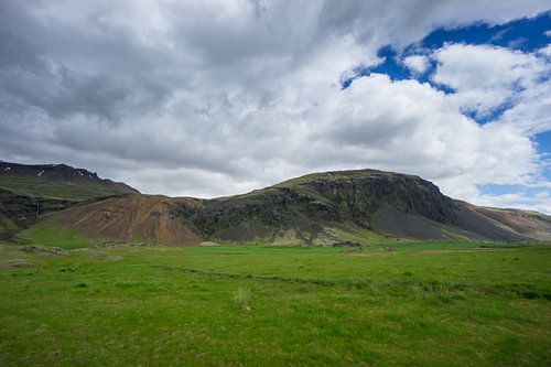IJsland - Groene vulkanische bergen met weide en bewolkte lucht
