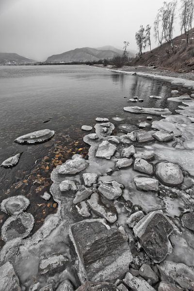 Icy rocky coast and a hill with trees in late by Michael Semenov