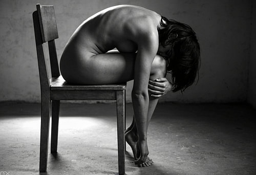 Bent Nude Figure on a Wooden Chair