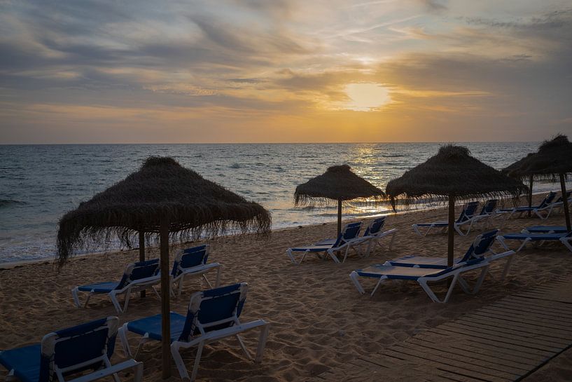 Sunset on the beach with sunbeds and umbrellas by Helga Golubew