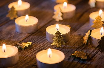 Christmas candlelight ornate with golden xmas trees on wooden table by Alex Winter