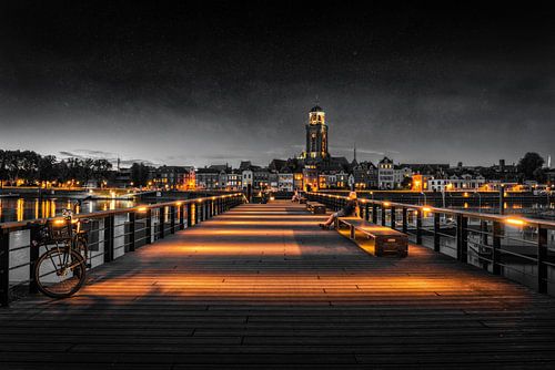 Iemand kijkt naar Deventer tijdens het blauwe uur aan de IJssel in zwart wit