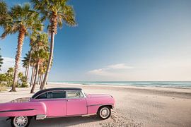 Pink 1960s Chevrolet on a sunny beach with palm trees
