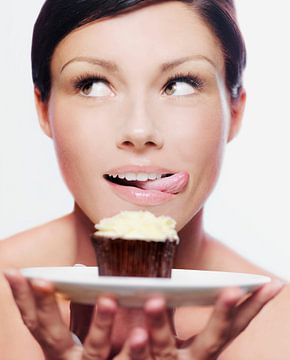 SF11289046 Vrouw die haar lippen aflikt bij een cupcake van BeeldigBeeld Food & Lifestyle