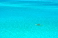 Man in een gele outrigger kano in de blauwe lagune van Bora Bora