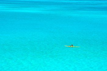 Homme dans une pirogue à balancier dans un lagon bleu