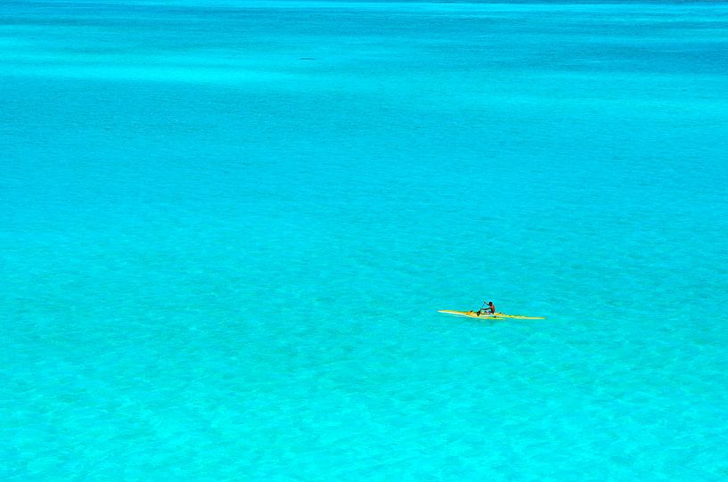 Man in an outrigger canoe in a blue lagoon by iPics Photography