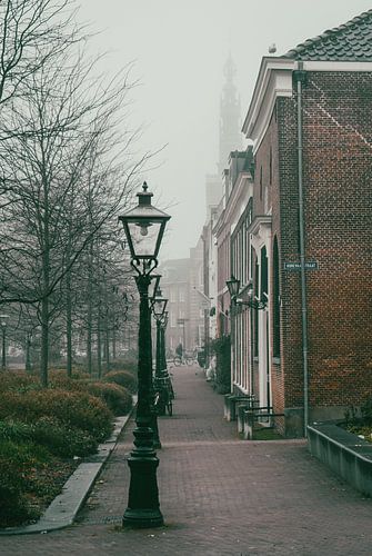 Foggy street scene in historic Dutch city - atmospheric cyclist in the distance