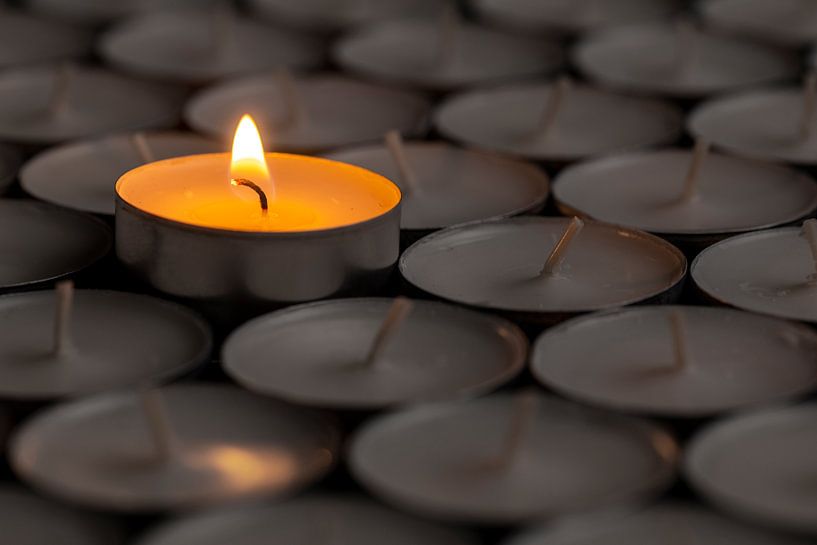 Flamme unique entre des bougies chauffe-plat sombres par Alexander Baumann